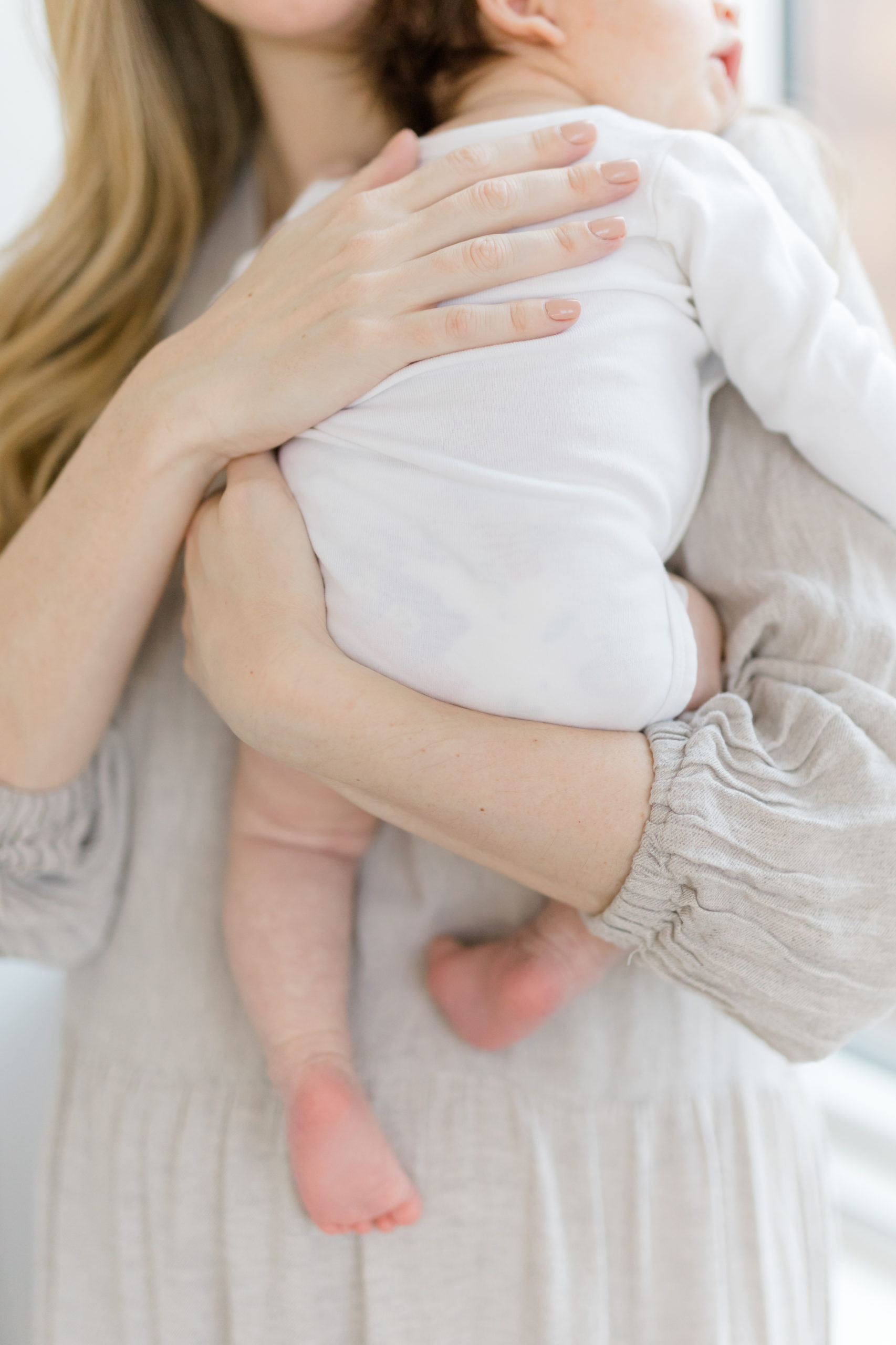 A mom holding her baby at an in home newborn photography session in NYC photographed by Jacqueline Clair Photography. 