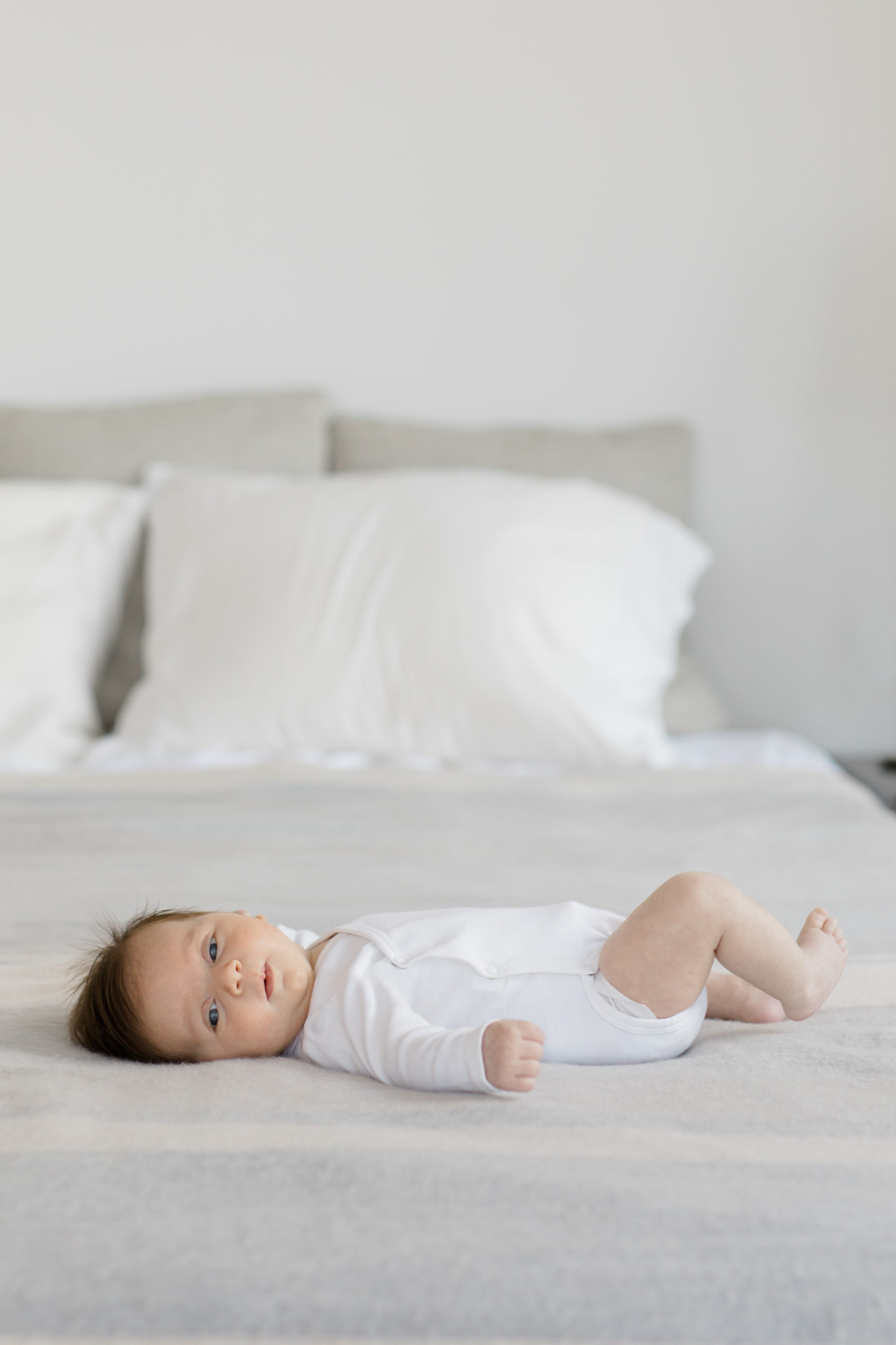 A newborn baby on a bed at an in home newborn photography session in NYC photographed by Jacqueline Clair Photography. 