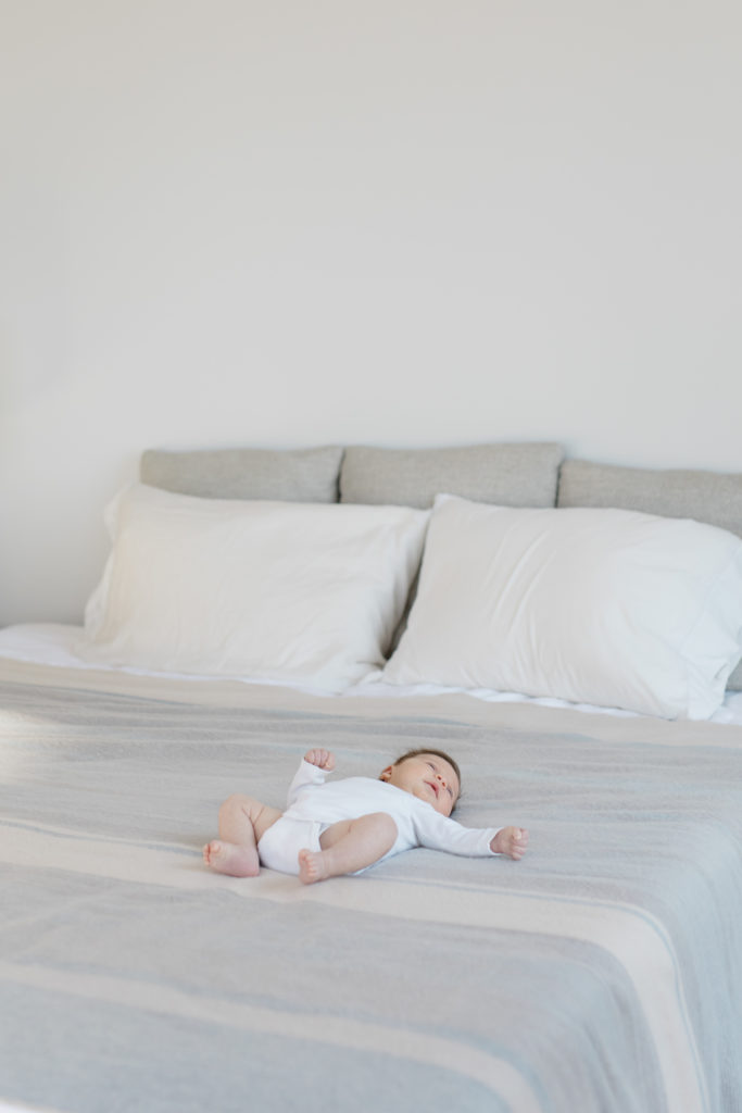A baby lays on a bed at an in home newborn photography session in NYC photographed by Jacqueline Clair Family Photography. 