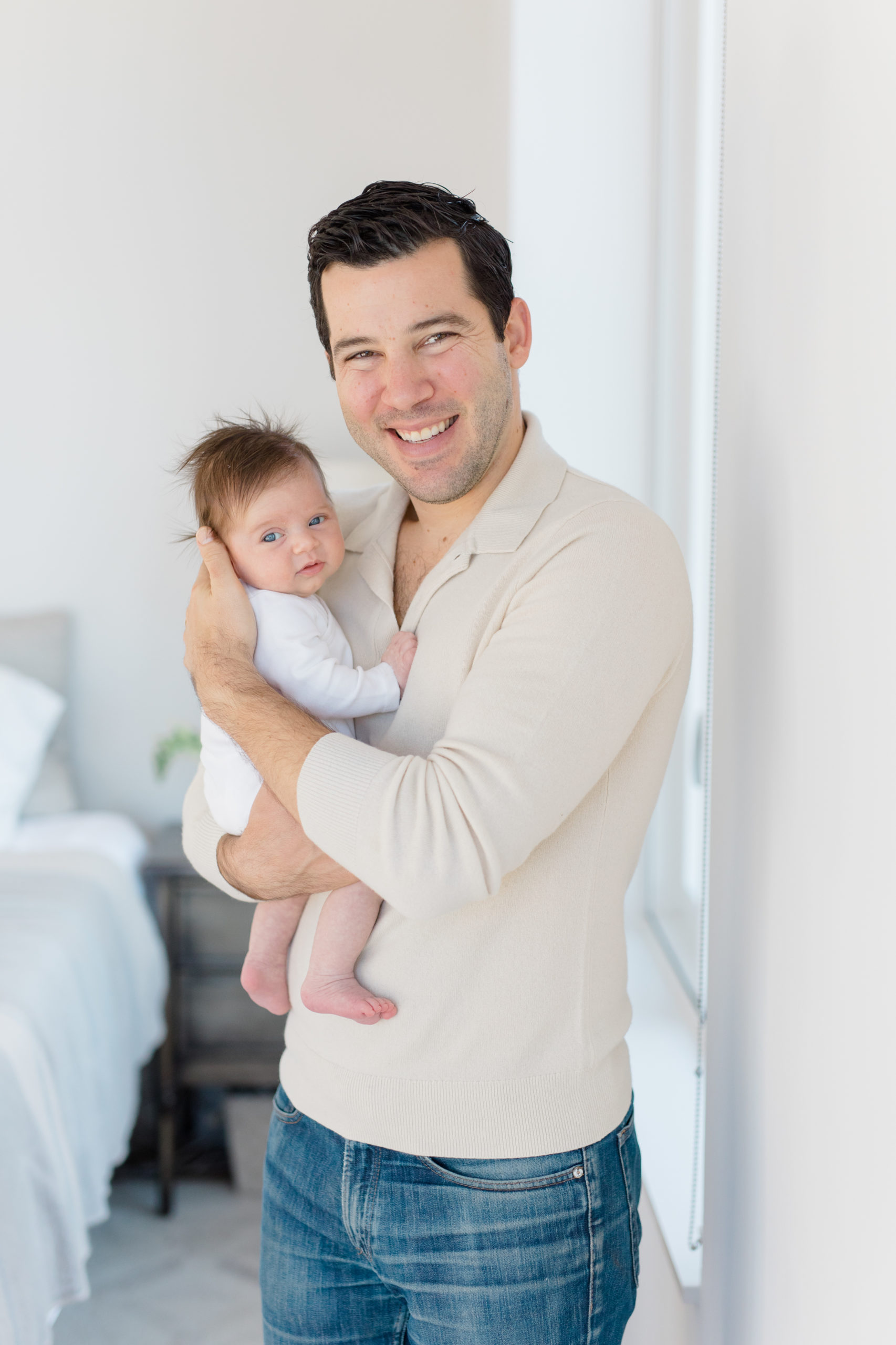 A dad holds his baby at an in home newborn photography session in NYC shot by Jacqueline Clair Photography. 