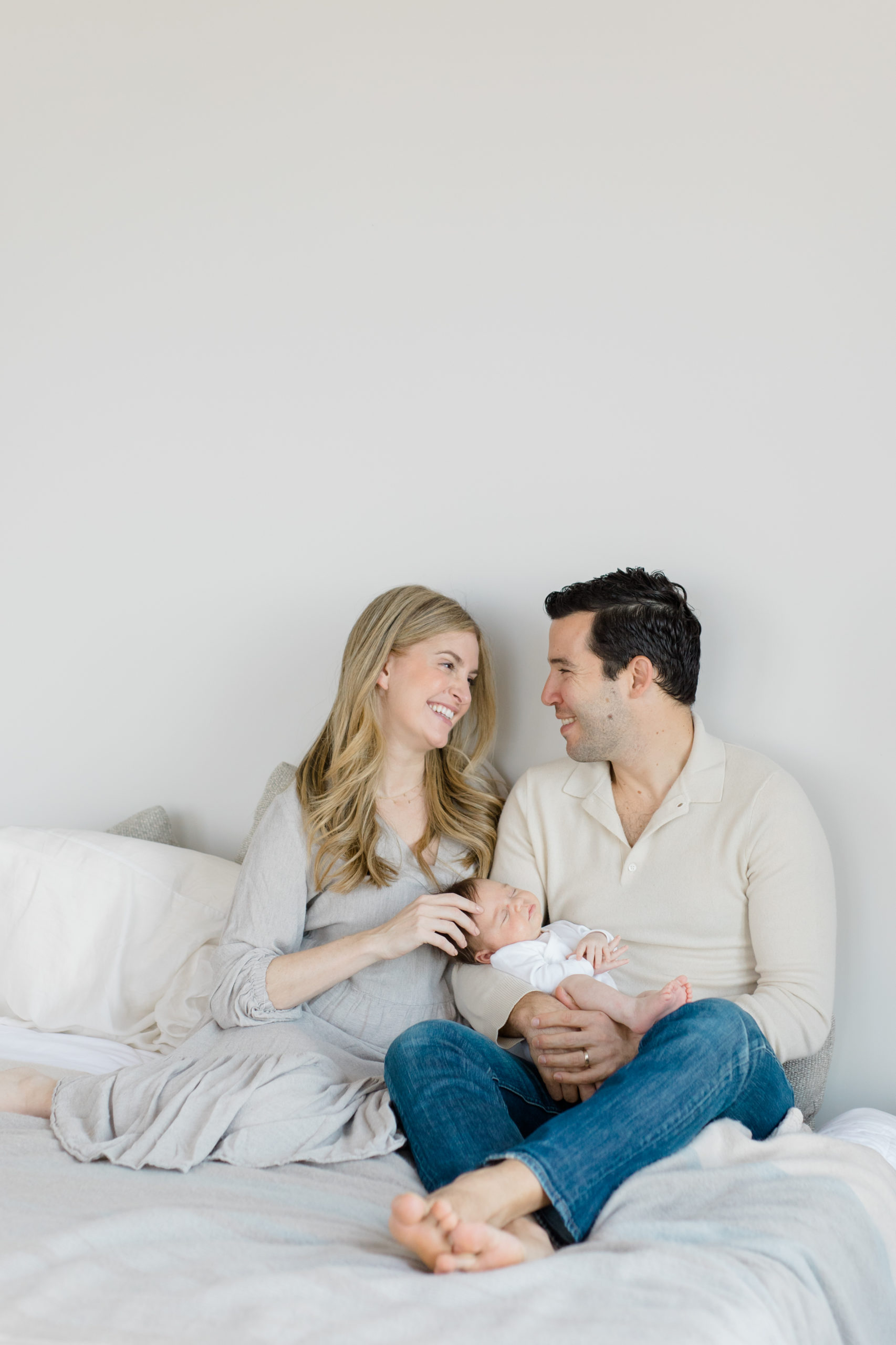 A mom and dad hold their baby at an in home newborn photography session in New York City shot by Jacqueline Clair Photography. 