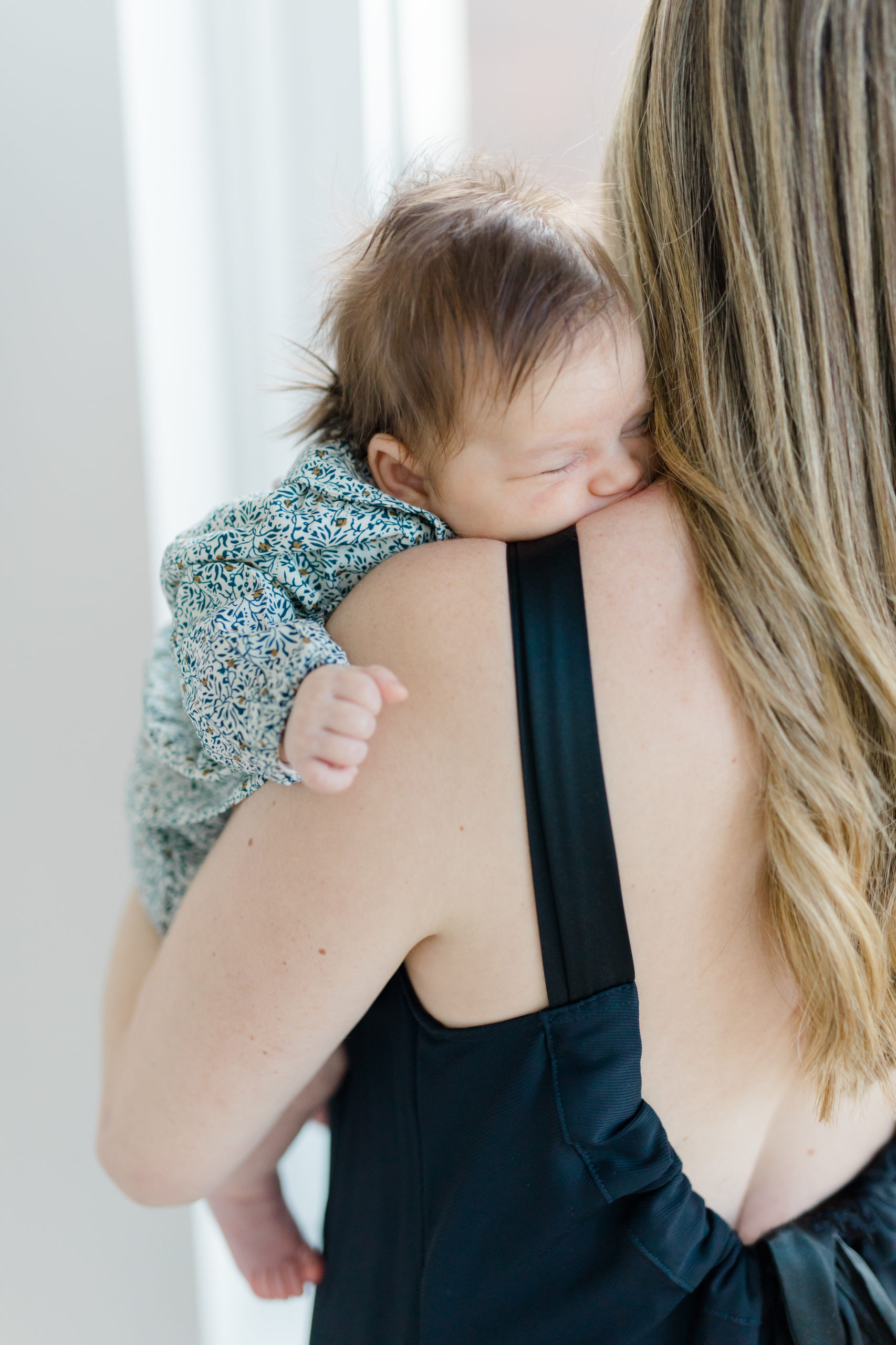 A baby on mom's shoulder at an in home newborn photography session in New York City shot by Jacqueline Clair Photography. 