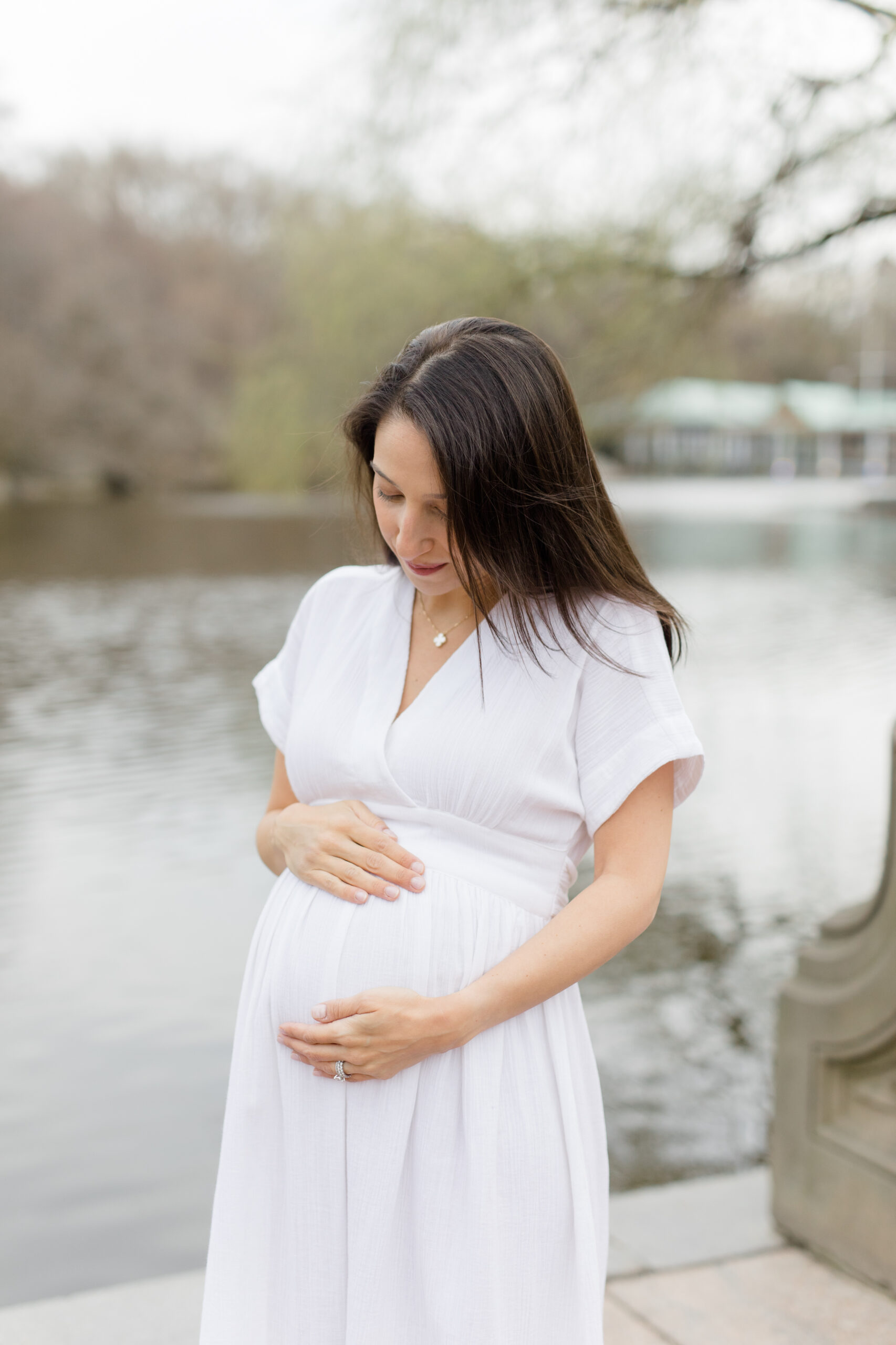An expecting mother looks at her bump in Central Park during a New York City maternity photography session with Jacqueline Clair Photography