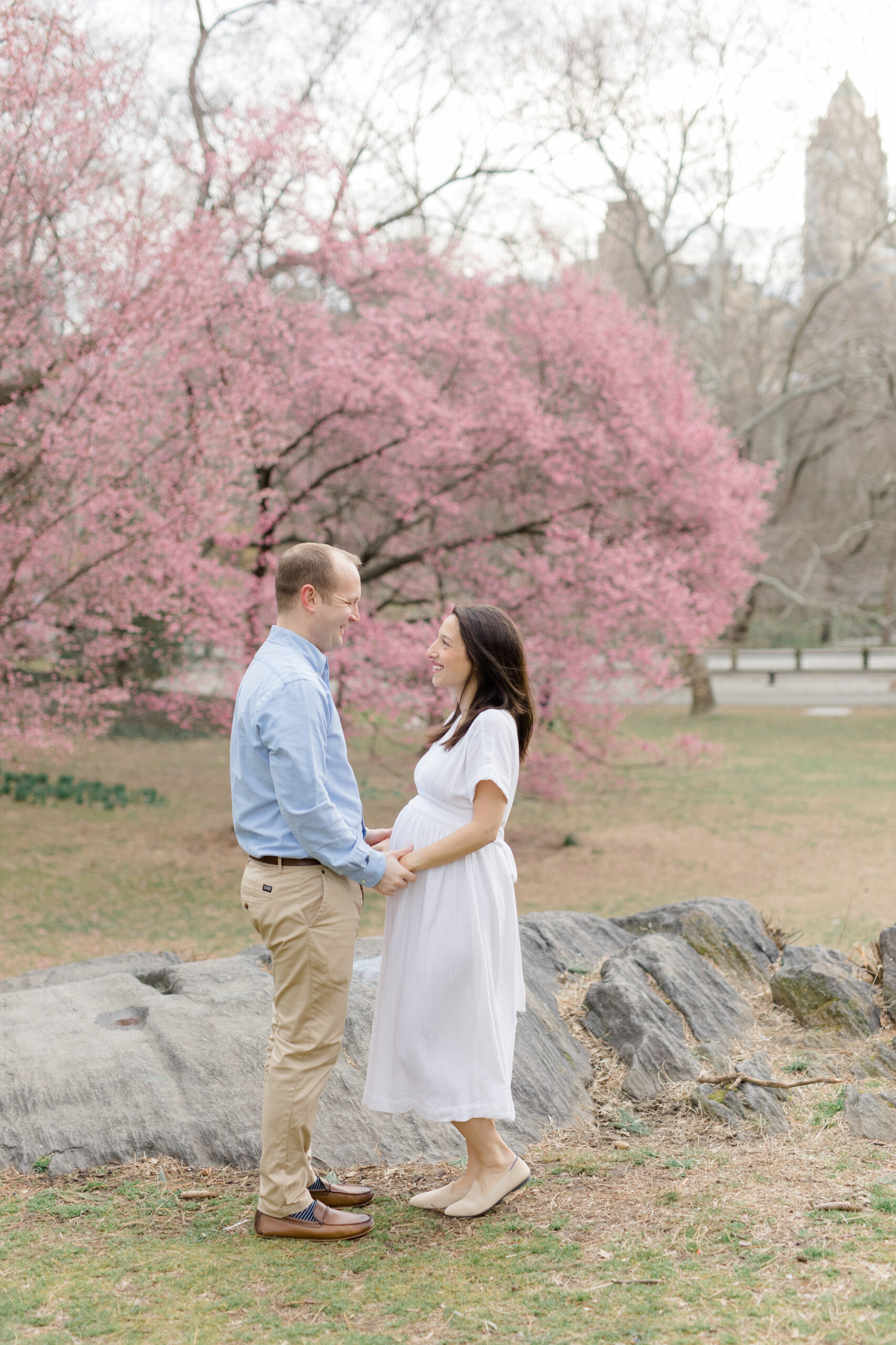 A pregnant couple smile at each other at a New York City maternity photography session with Jacqueline Clair Photography