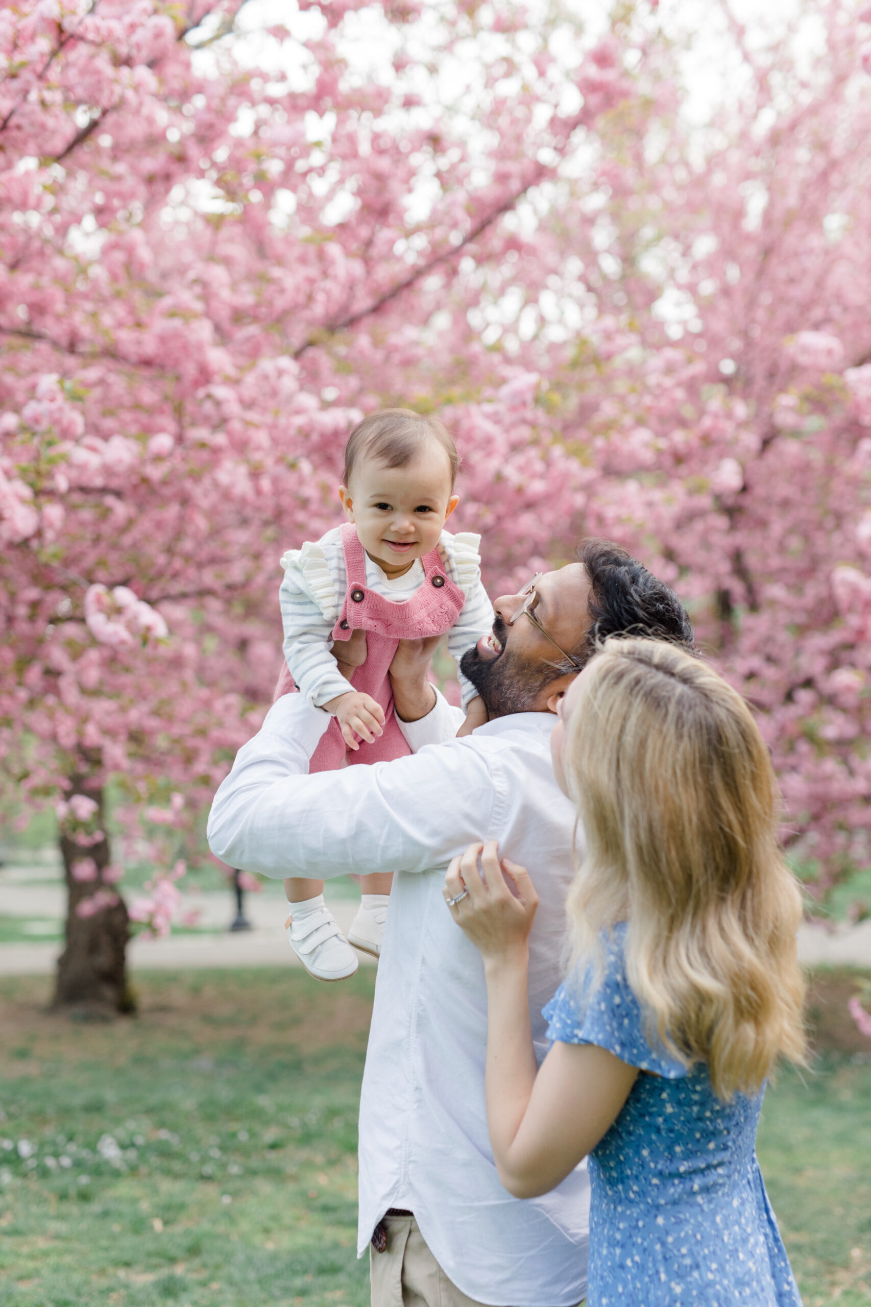 A dad and mom with their baby at a spring mini session in Central Park, shot by Jacqueline Clair Photography
