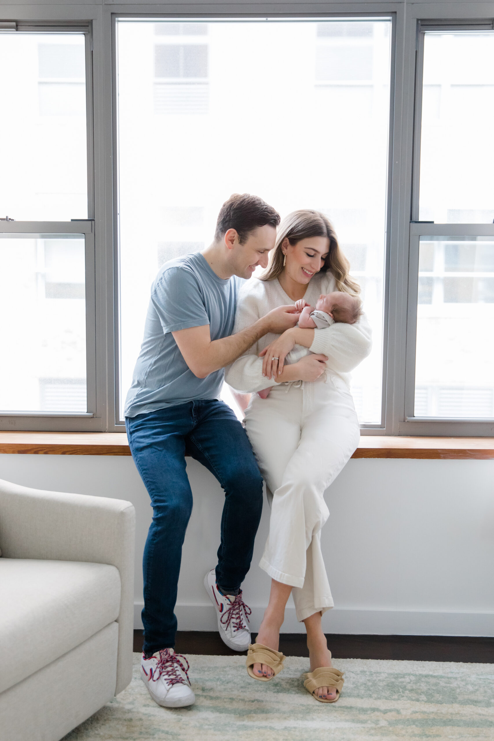 A mom and dad look at their baby at a newborn session with New York City newborn photographer Jacqueline Clair