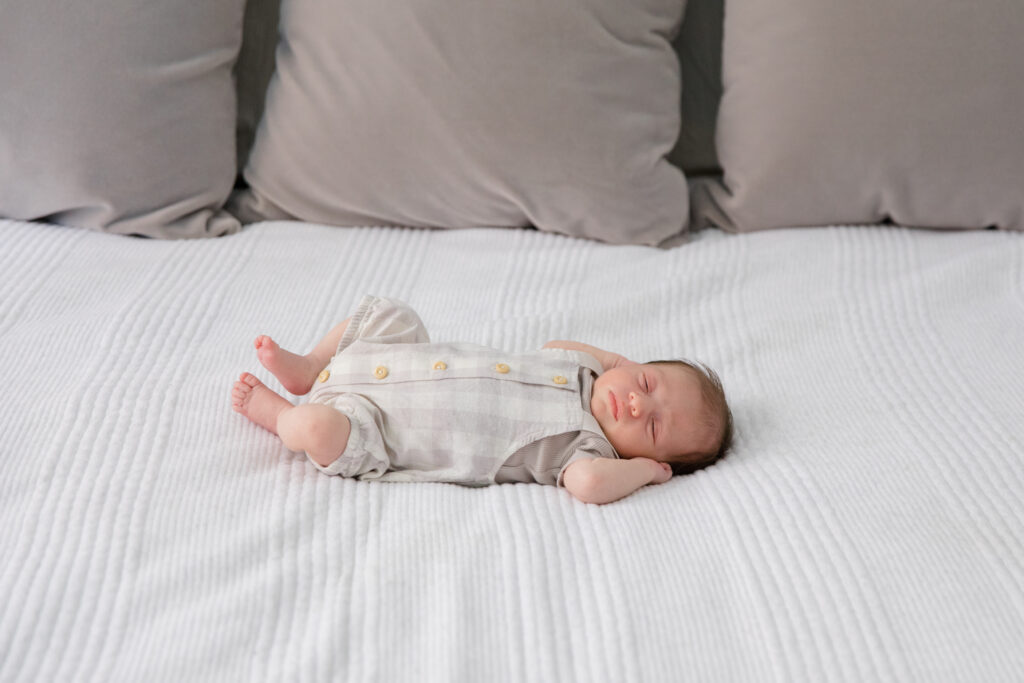 A baby rests on a bed at a newborn session with New York City newborn photographer Jacqueline Clair