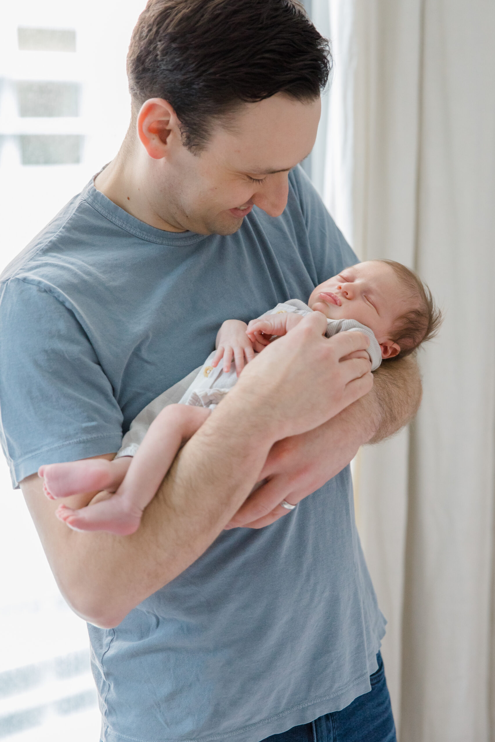 A dad holds his baby at a newborn session with New York City newborn photographer Jacqueline Clair