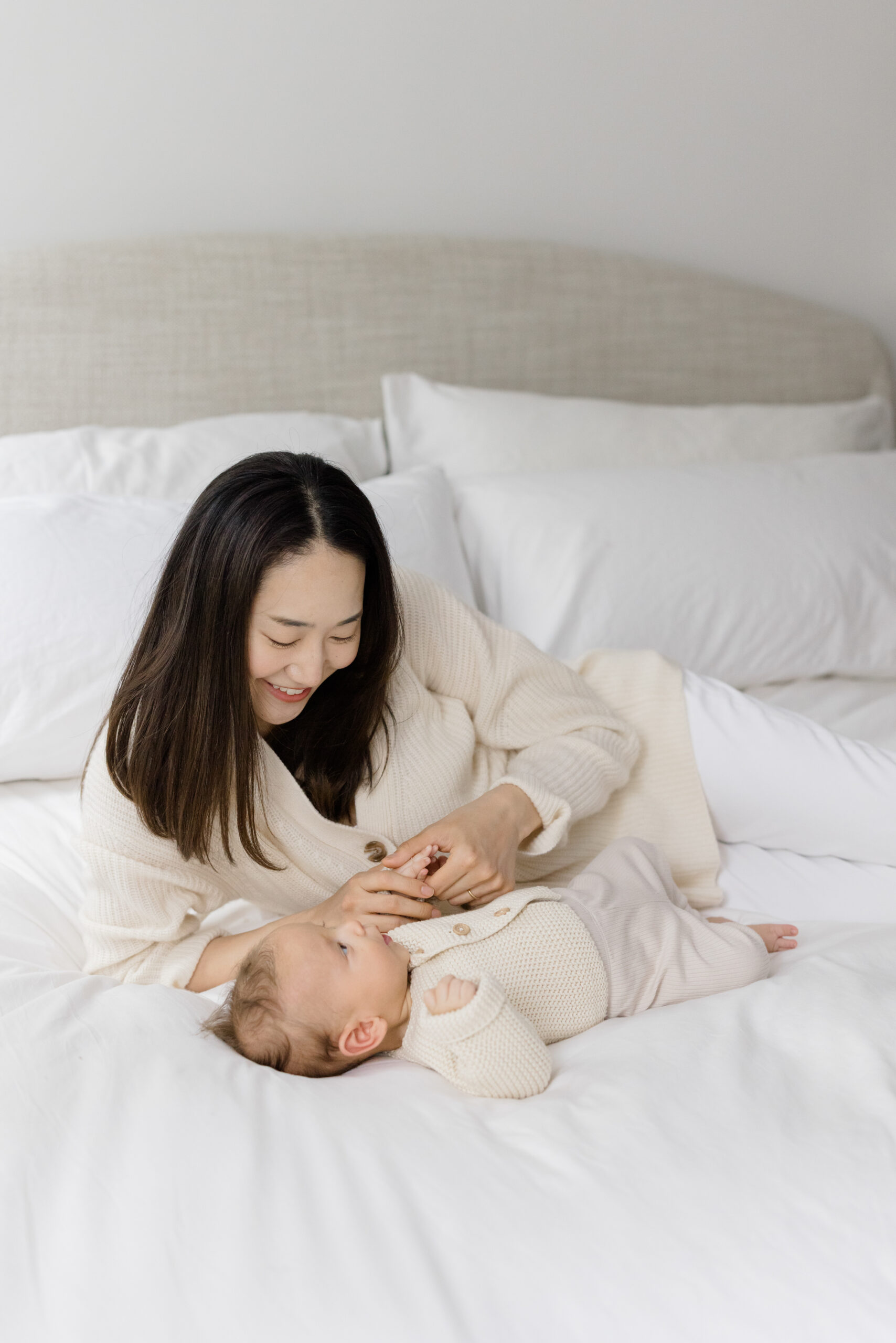 A mother reclining on the bed with her baby as an example of what to wear for your lifestyle newborn session 