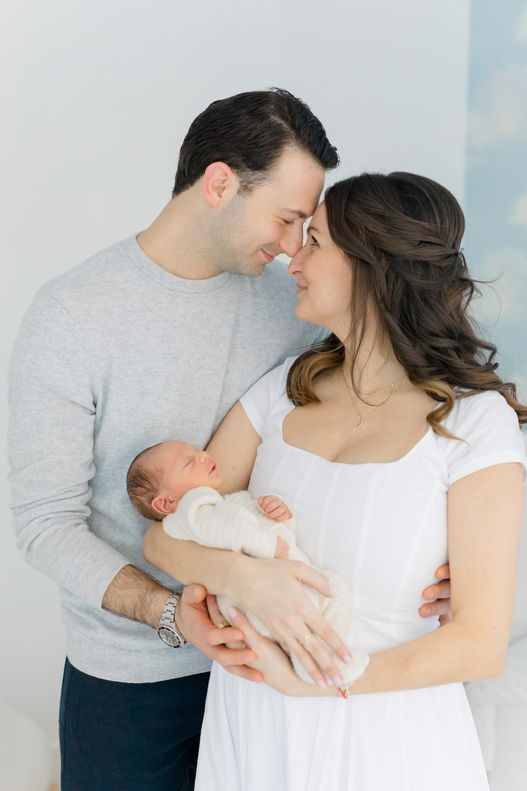 A husband and wife with their baby as an example of what to wear for your lifestyle newborn session 