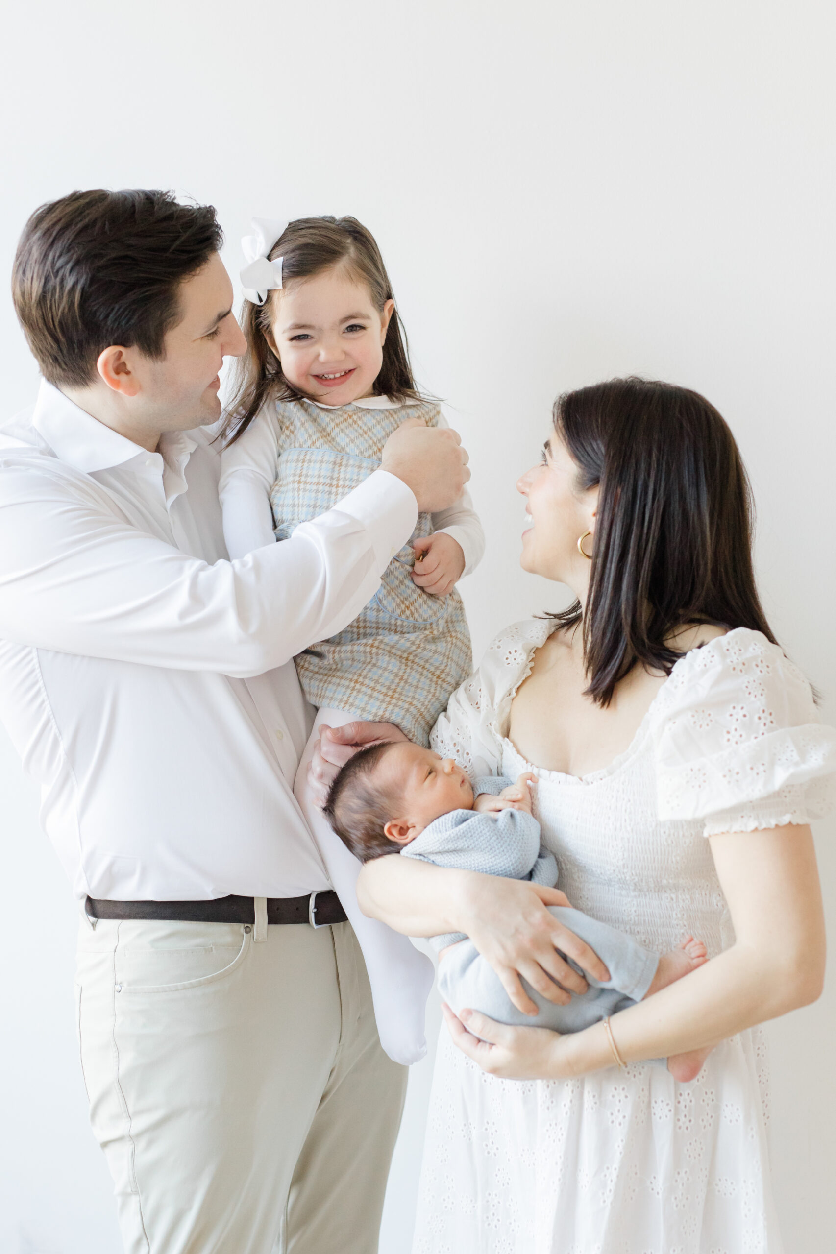 A family of four wearing shades of white, khaki, and blue at a lifestyle newborn session 