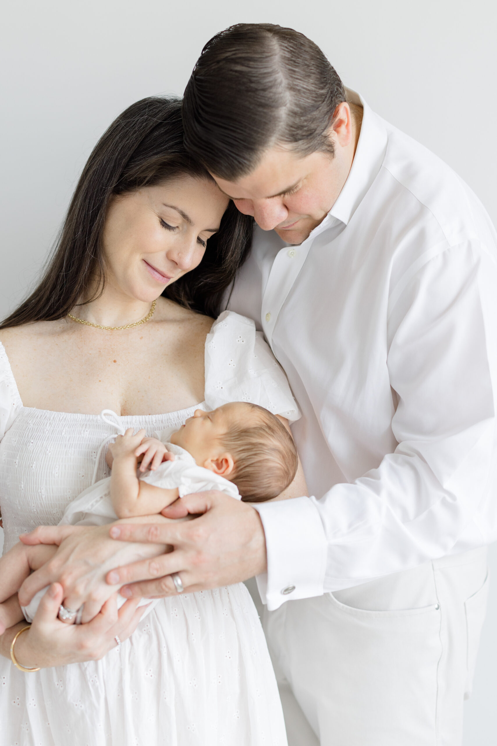 A husband and wife dressed in white at their lifestyle newborn session 