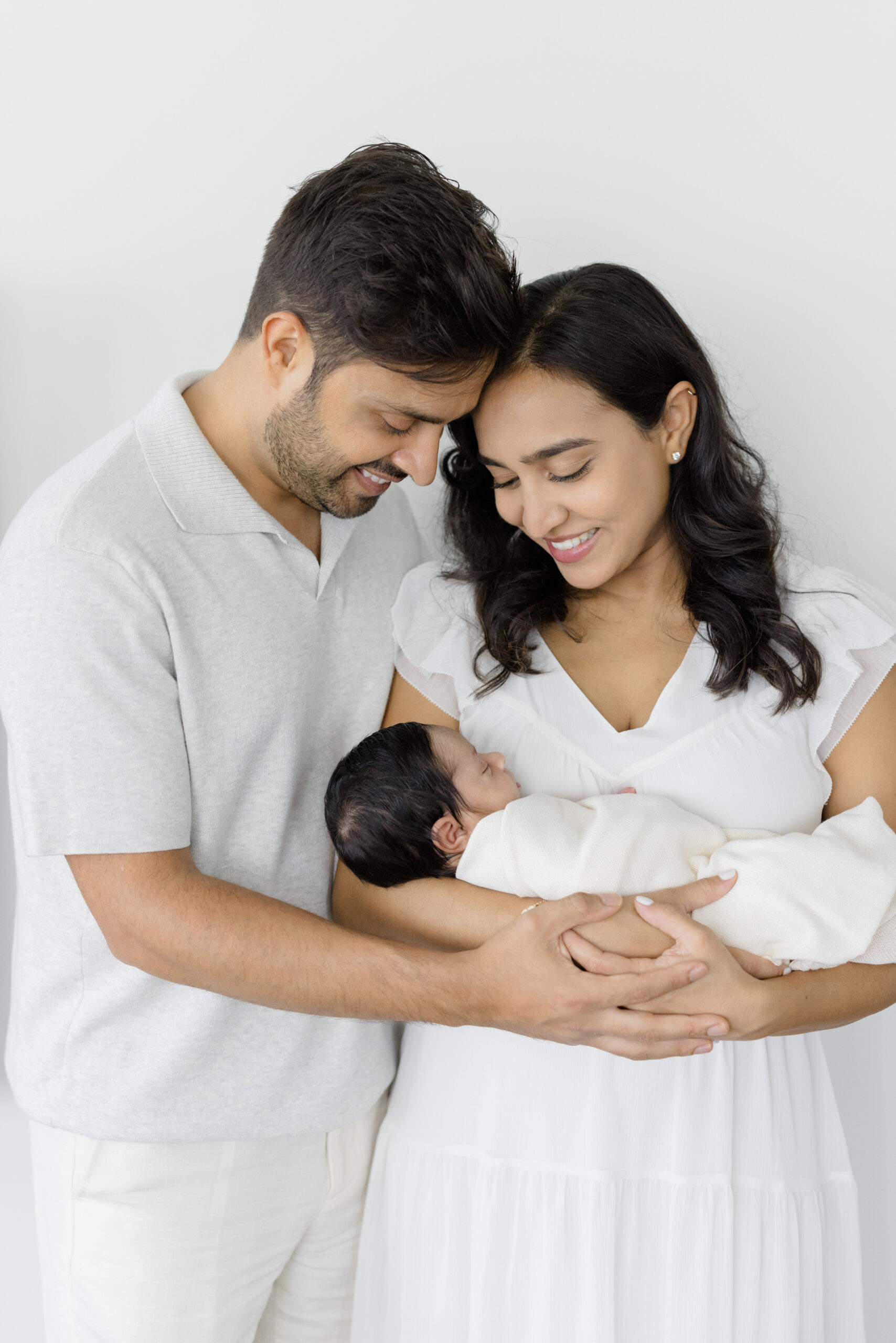 A husband and wife wearing soft neutral colors at their lifestyle newborn session