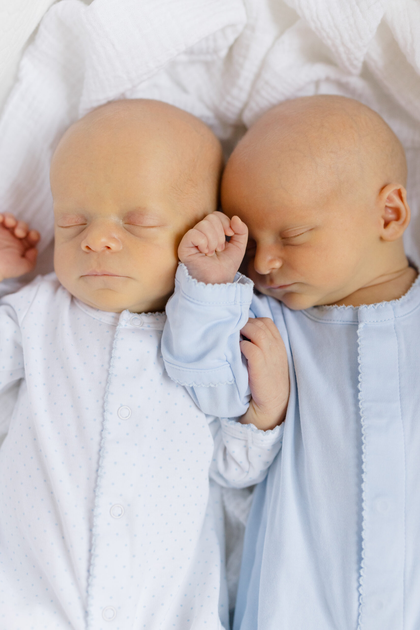 Twin boys in white and blue onesies at their lifestyle newborn session 