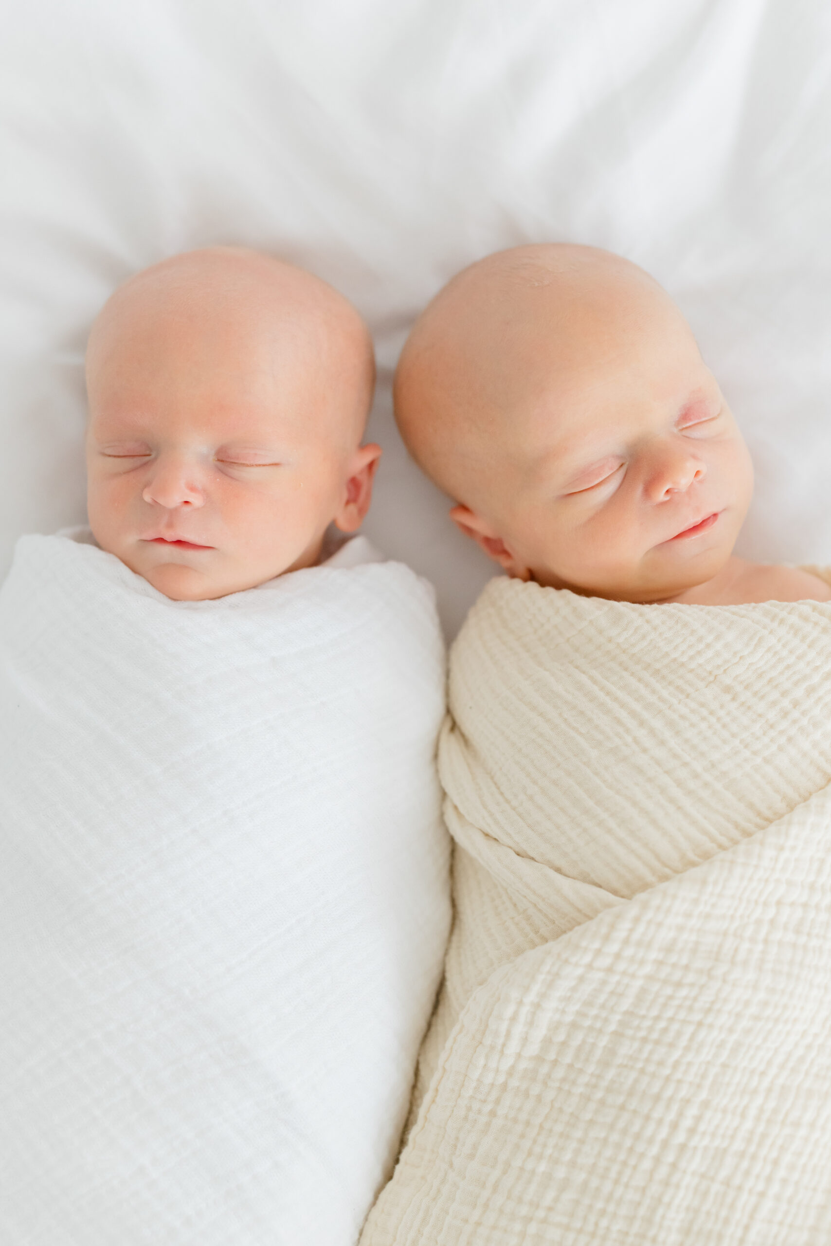 Twin boys in neutral colored swaddles at their lifestyle newborn session 