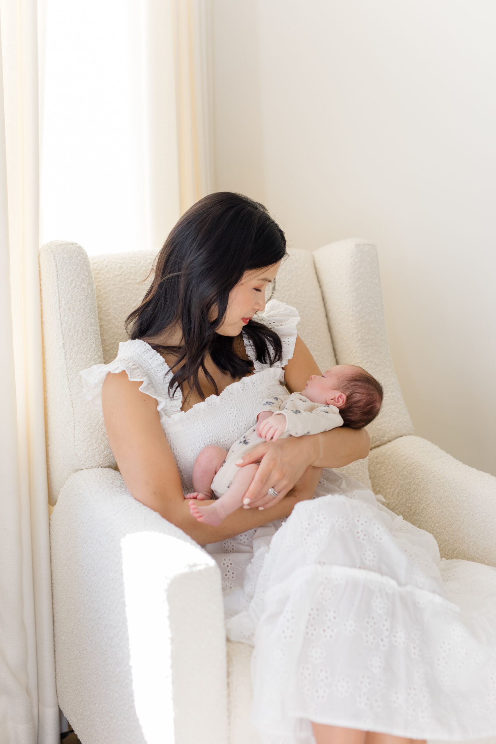 A woman wearing a white dress with her baby as an example of what to wear for your lifestyle newborn session 